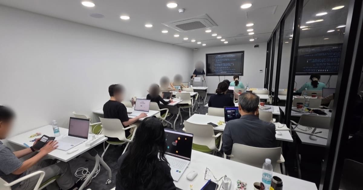 강의실에서 선생님들이 노트북으로 실습하고, 앞쪽 화면 앞에서 강사가 설명하는 워크숍 장면. 참석자 얼굴은 흐리게 가렸다